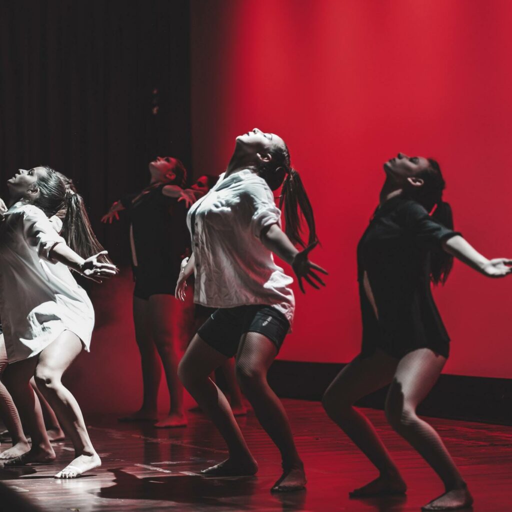 A picture of a dance performance showing a lit up cyclorama and dancers