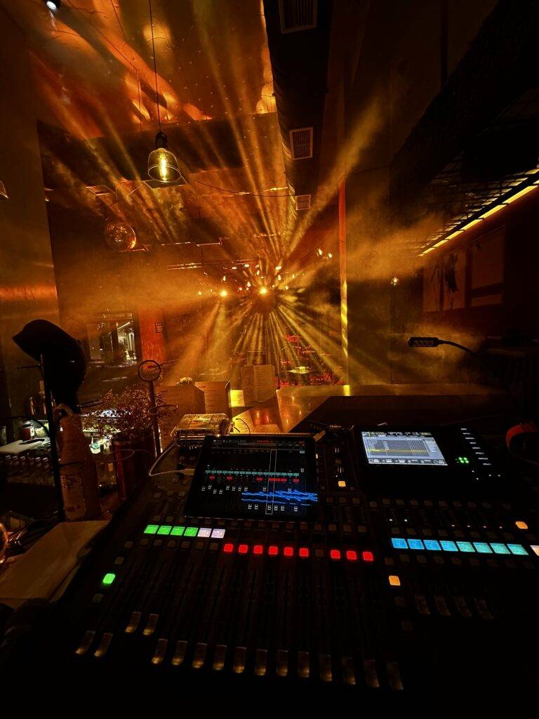 A behringer X32 console and beam moving head lights in the background