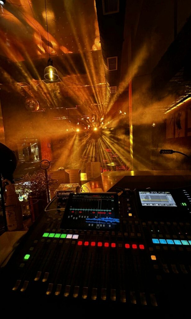 A behringer X32 console and beam moving head lights in the background